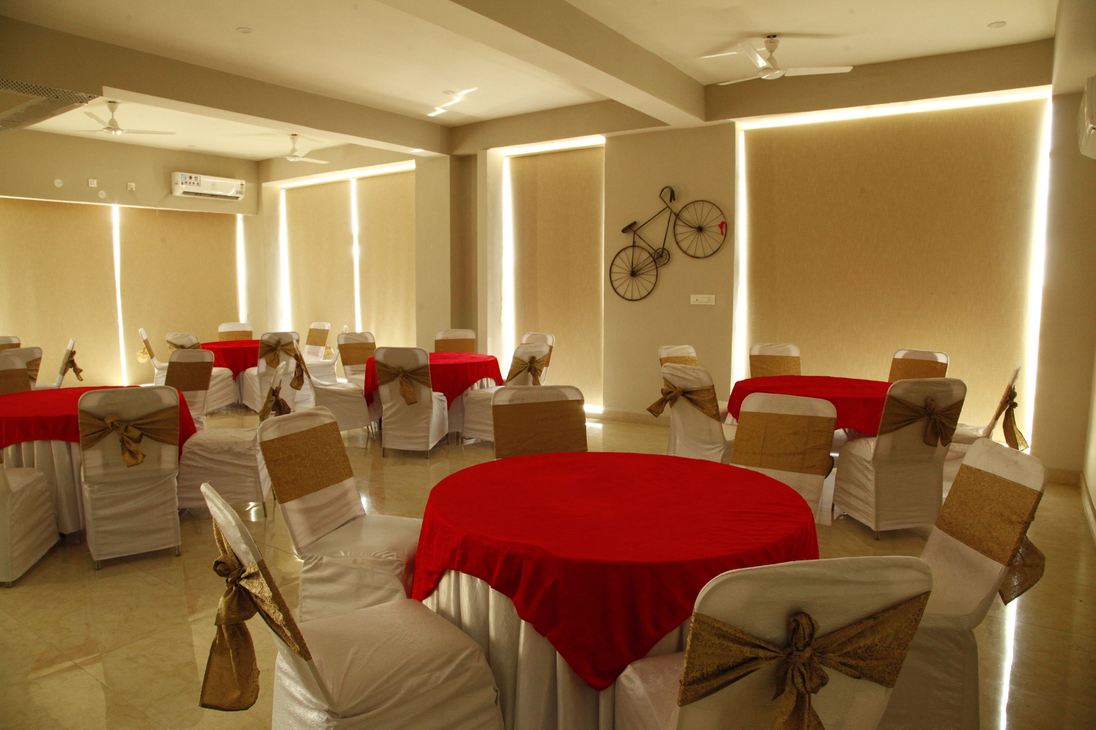 A conference room with round tables, white chairs with red and gold sashes, and a wall-mounted bicycle decoration.