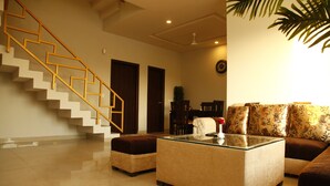 A spacious living area with a staircase, a glass coffee table, and patterned sofas. - Anandam Clarks Inn Suites Vrindavan (Mathura)