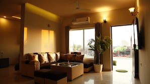 A living room with a sofa set, a coffee table, and a potted plant. - Anandam Clarks Inn Suites Vrindavan (Mathura)