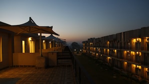 A hotel corridor with multiple rooms, each featuring a balcony and a covered seating area. - Anandam Clarks Inn Suites Vrindavan (Mathura)
