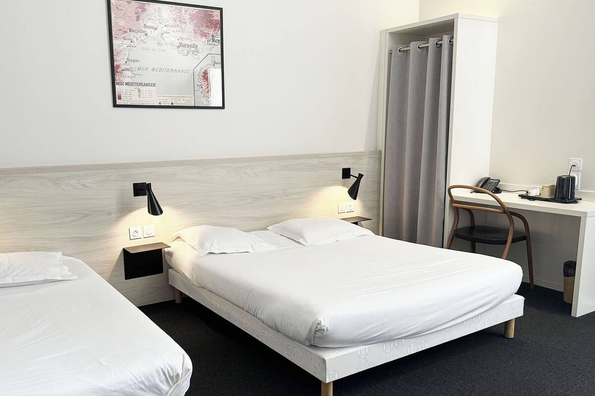 Habitación de hotel con dos camas individuales, un escritorio con silla, un mapa en la pared y una cortina.