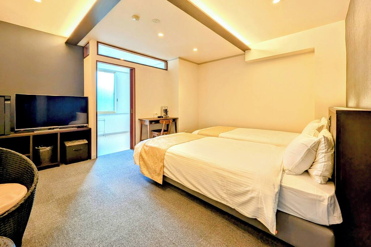 Una habitación de hotel moderna con una cama grande, televisión y escritorio.