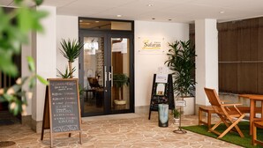 Ein Restaurant mit Eingang, einer Schautafel und einem Holztisch mit Stühlen.