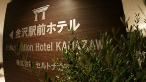 Ein Holzschild mit japanischem Text und einem stilisierten Hotel-Symbol, das den Weg zum Hotel weist.