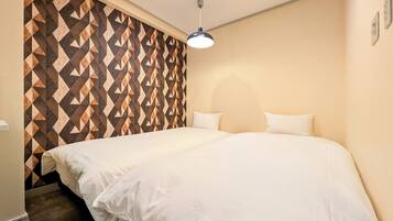 A hotel room with a large bed, a geometric-patterned wall, and a ceiling light.