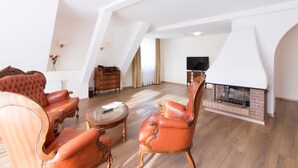 Un salón amplio con chimenea, sillones de cuero, una mesa de centro de madera y un televisor.