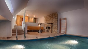 Una piscina con un muro de piedra y una escalera de madera.