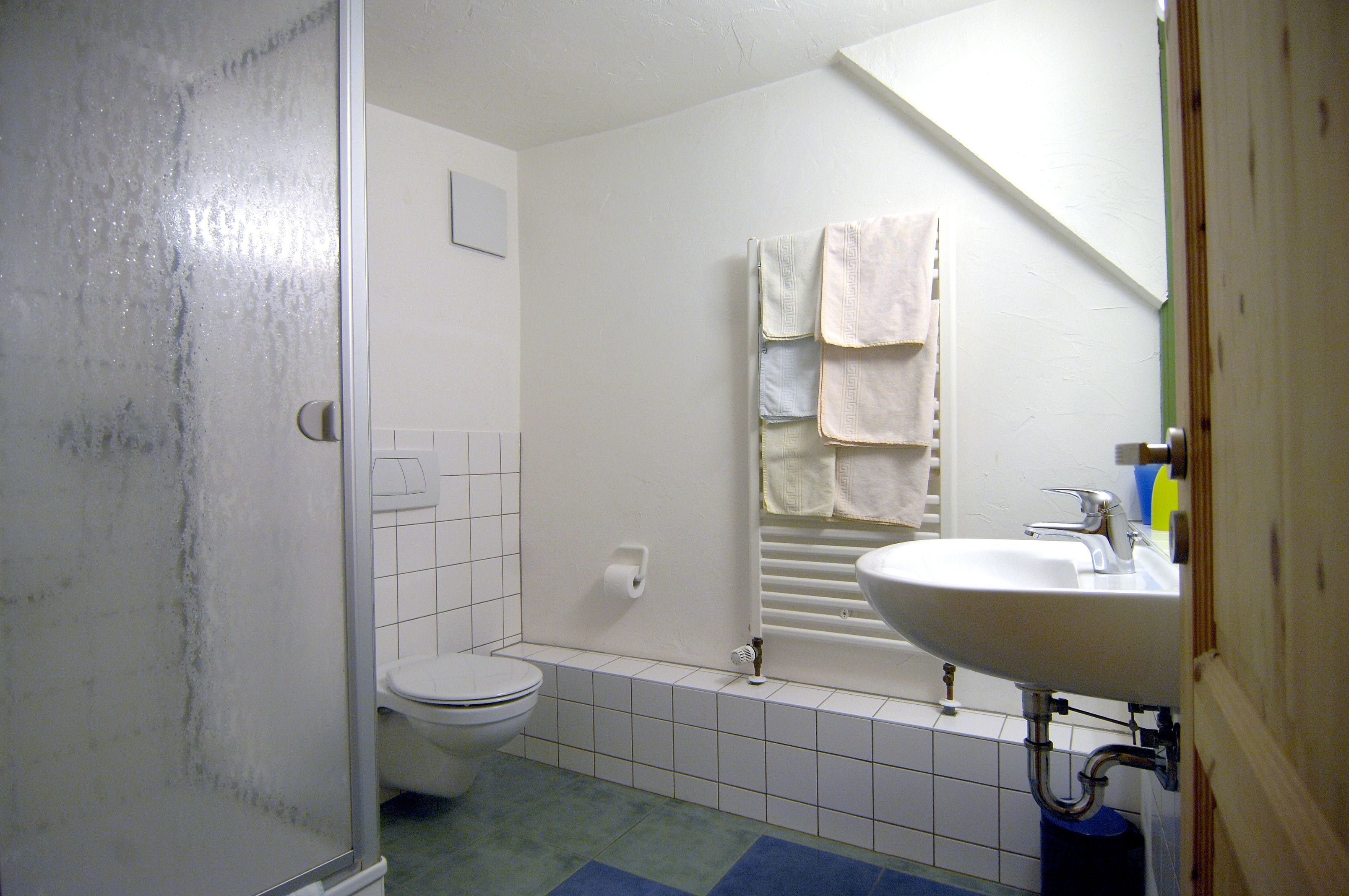 Et badeværelse med toilet, vask og brusebad.
