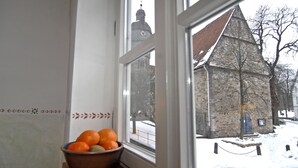 Una ventana con vista a un edificio de piedra y una calle cubierta de nieve.
