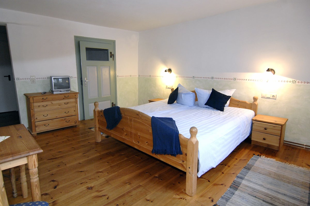 Une chambre à coucher avec un lit en bois, des tables de chevet, une commode et un téléviseur.