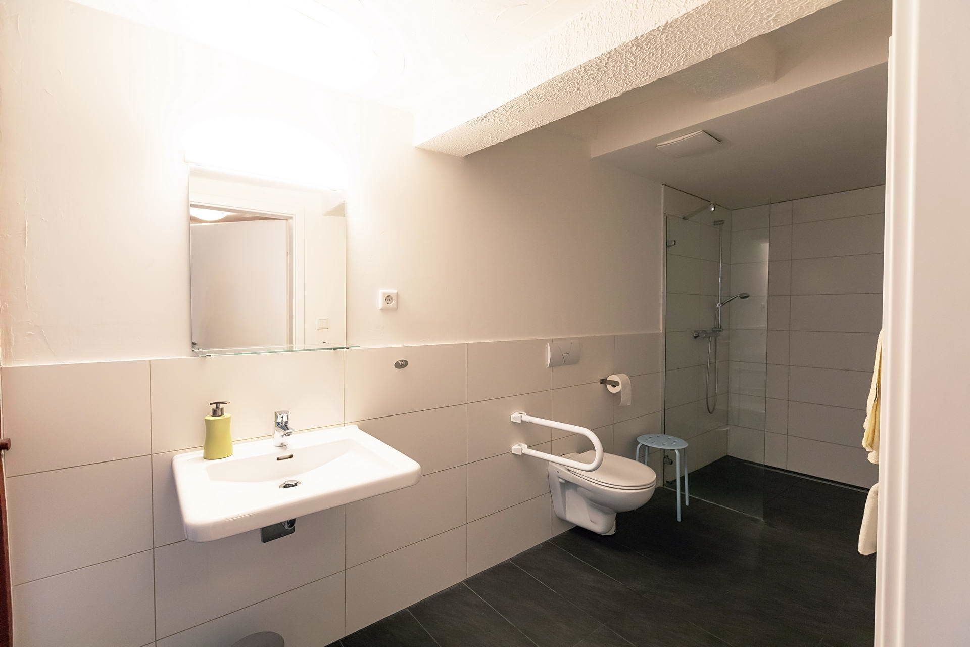 Un baño moderno con lavamanos, espejo e inodoro blancos.