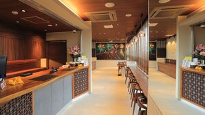 Eine moderne Hotelhalle mit einer Rezeption, einer Sitzecke und einer Stadtkarte an der Wand.