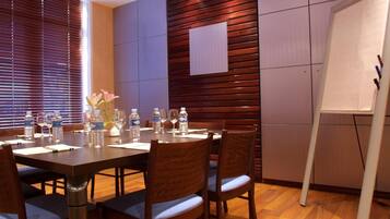 A conference room with a wooden table, chairs, a whiteboard, and a window with blinds.