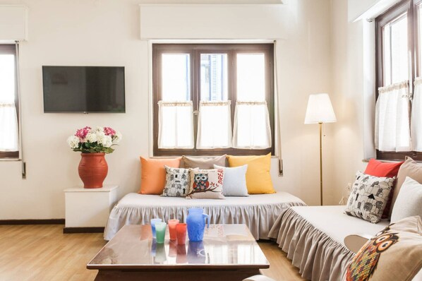 Une chambre à coucher comprenant un lit, une table de chevet, une lampe et un téléviseur fixé au mur.