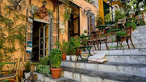 A building with outdoor seating, potted plants, and a staircase leading to the entrance. - Nephiria's Art House, Under the Acropolis (Athens)