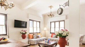 A spacious living room with a wooden floor, a sofa set, a coffee table, and two large windows with curtains. - Nephiria's Art House, Under the Acropolis (Athens)