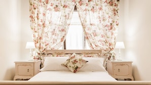 A bedroom with a bed, floral curtains, two bedside tables with lamps, and a nightstand. - Nephiria's Art House, Under the Acropolis (Athens)