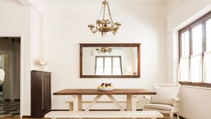 A dining area with a wooden table, white bench, and a chandelier. - Nephiria's Art House, Under the Acropolis (Athens)