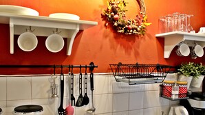 A kitchen with white cabinets, a stove, and various utensils hanging on the wall. - Nephiria, Under the Acropolis, In the heart of Plaka (Athens)