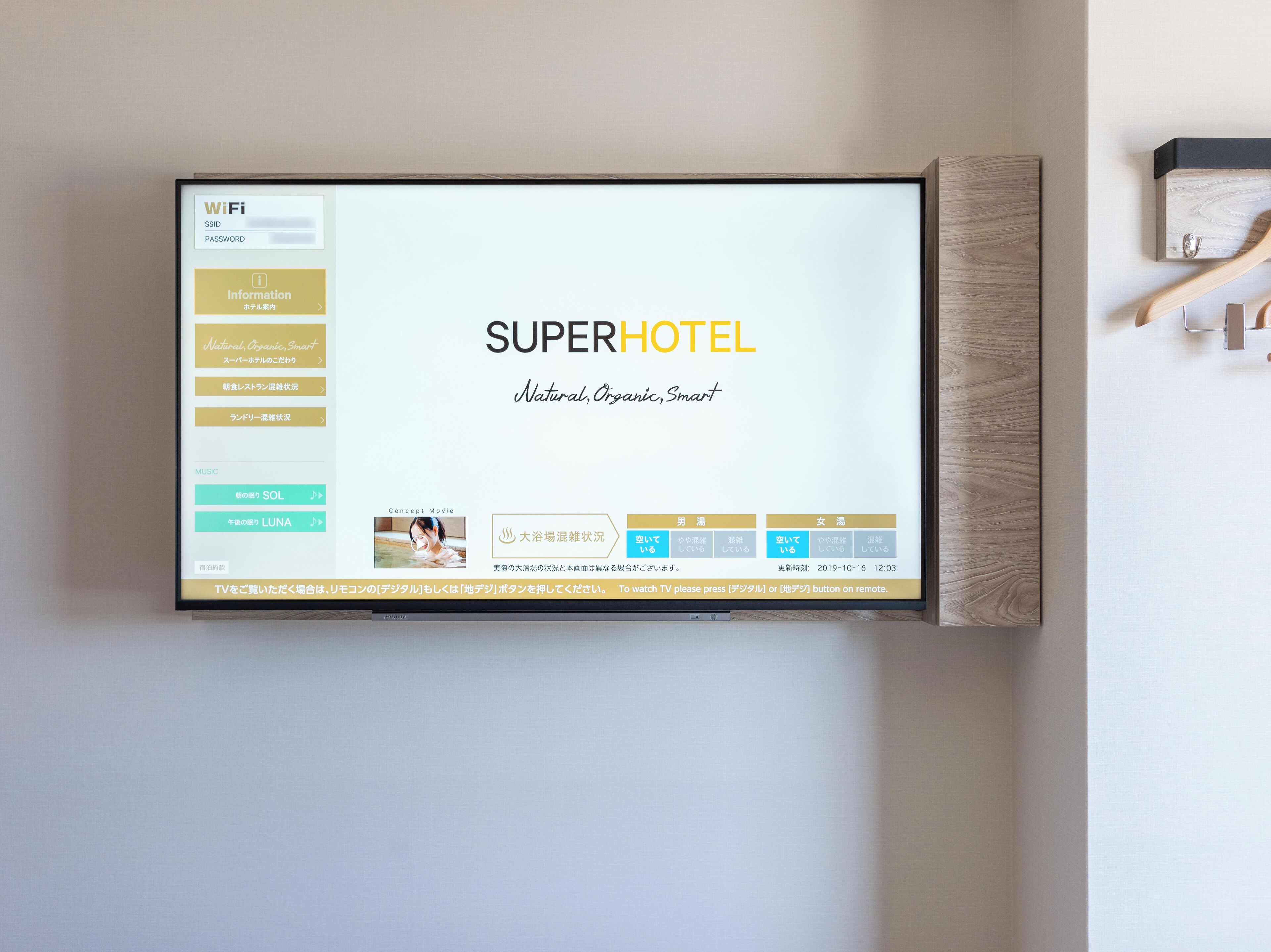Habitación de hotel con una pantalla grande mostrando el nombre y los servicios del hotel.