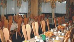 A banquet hall with rows of wooden chairs and tables set for a meal. - AdiHotels 'Haus Gombert' (Knullwald)