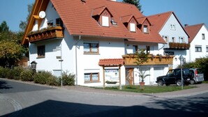 A two-story building with a red-tiled roof, a balcony, and a sign indicating a restaurant. - AdiHotels 'Haus Gombert' (Knullwald)