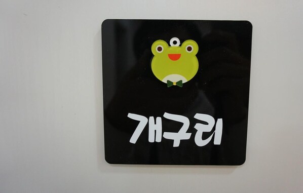 A black sign with a cartoon frog and Korean text. - Wansangol Guesthouse (Jeonju)