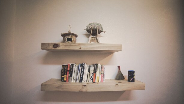 Two wooden shelves with books and decorative items. - Wansangol Guesthouse (Jeonju)