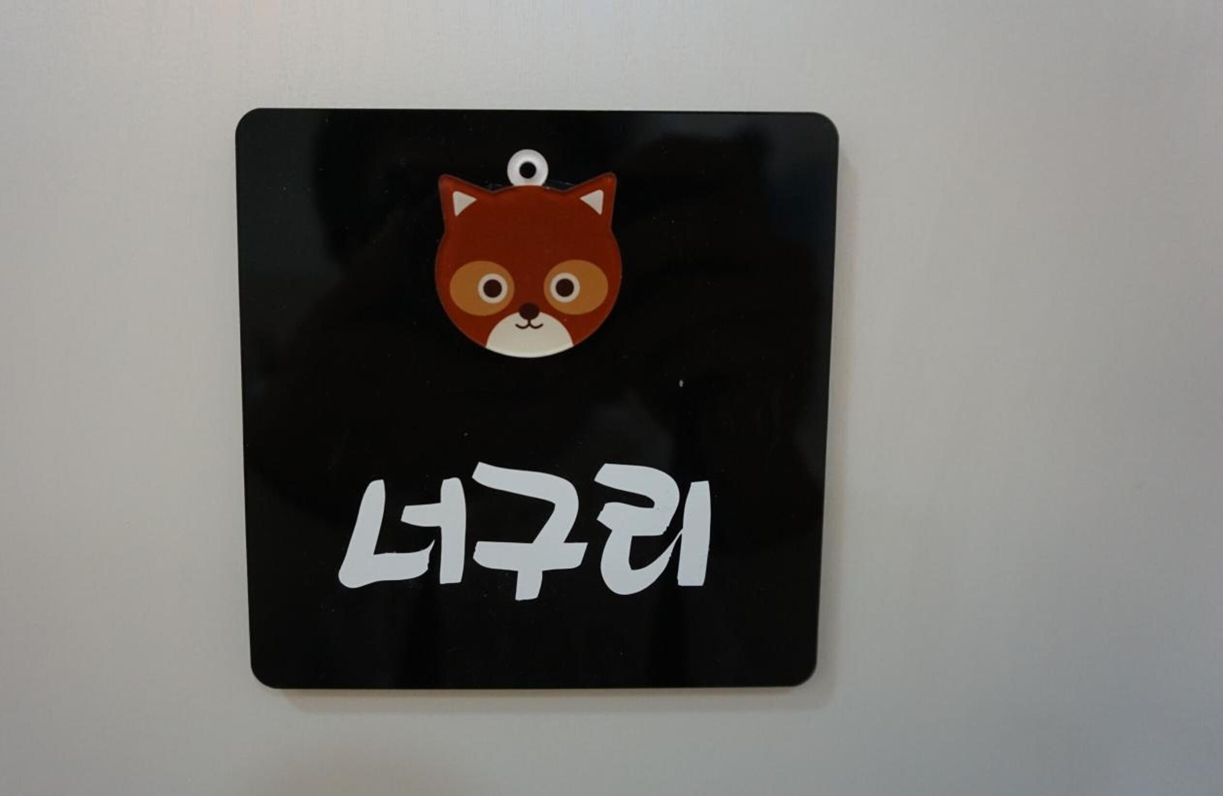 A black sign with a cartoon fox and Korean text.