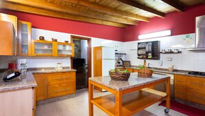 Una cocina con armarios de madera, encimera de granito y pared roja.