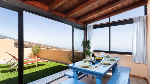Un comedor con una mesa dispuesta para cuatro, una planta en maceta y vistas del paisaje.
