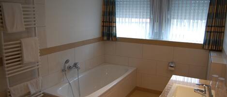 A bathroom with a bathtub, a sink, and a towel rack.