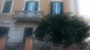 A multi-story building with a symmetrical facade, featuring a central balcony with a balustrade, and a gated entrance. - Equilibrì Guest House (Rome)