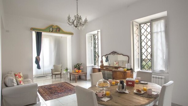 A bright dining area with a wooden table set for breakfast, surrounded by white chairs. - Equilibrì Guest House (Rome)