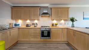 A modern kitchen with wooden cabinets, a built-in microwave, a gas stove, and a stainless steel oven. - Harris Retreat - Donnini Apartments (Ayr)
