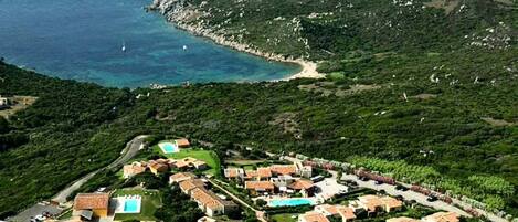 A coastal resort with villas, a swimming pool, and a view of the sea.