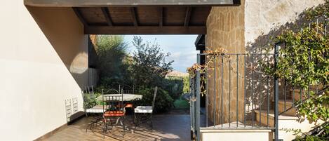 Un patio al aire libre con una mesa, sillas, una pérgola y una escalera que lleva a un edificio de piedra.