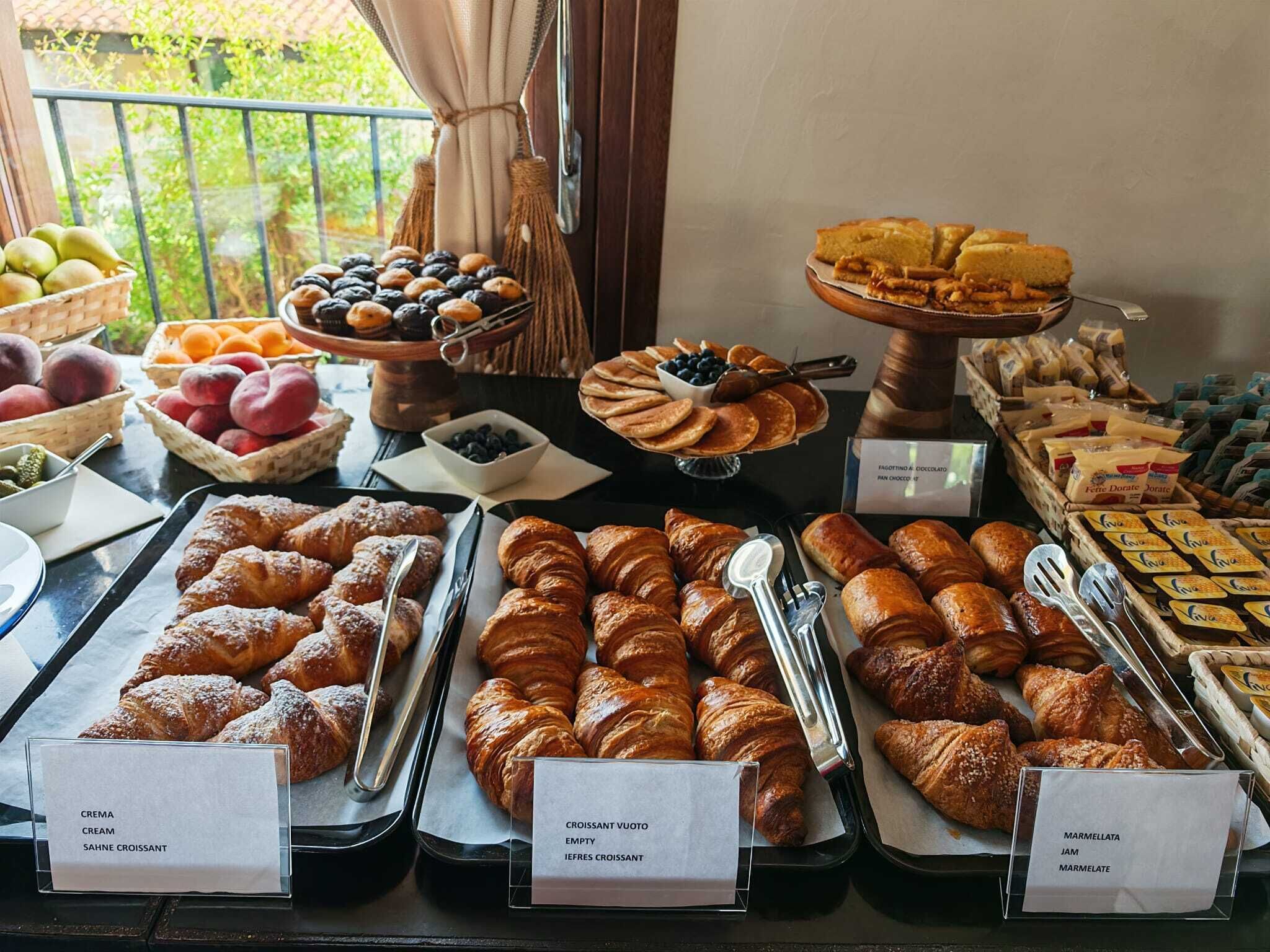 A breakfast buffet with various pastries, fruits, and cheeses.