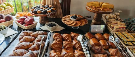 Un buffet de petit-déjeuner proposant un assortiment de viennoiseries, de fruits et de fromages.