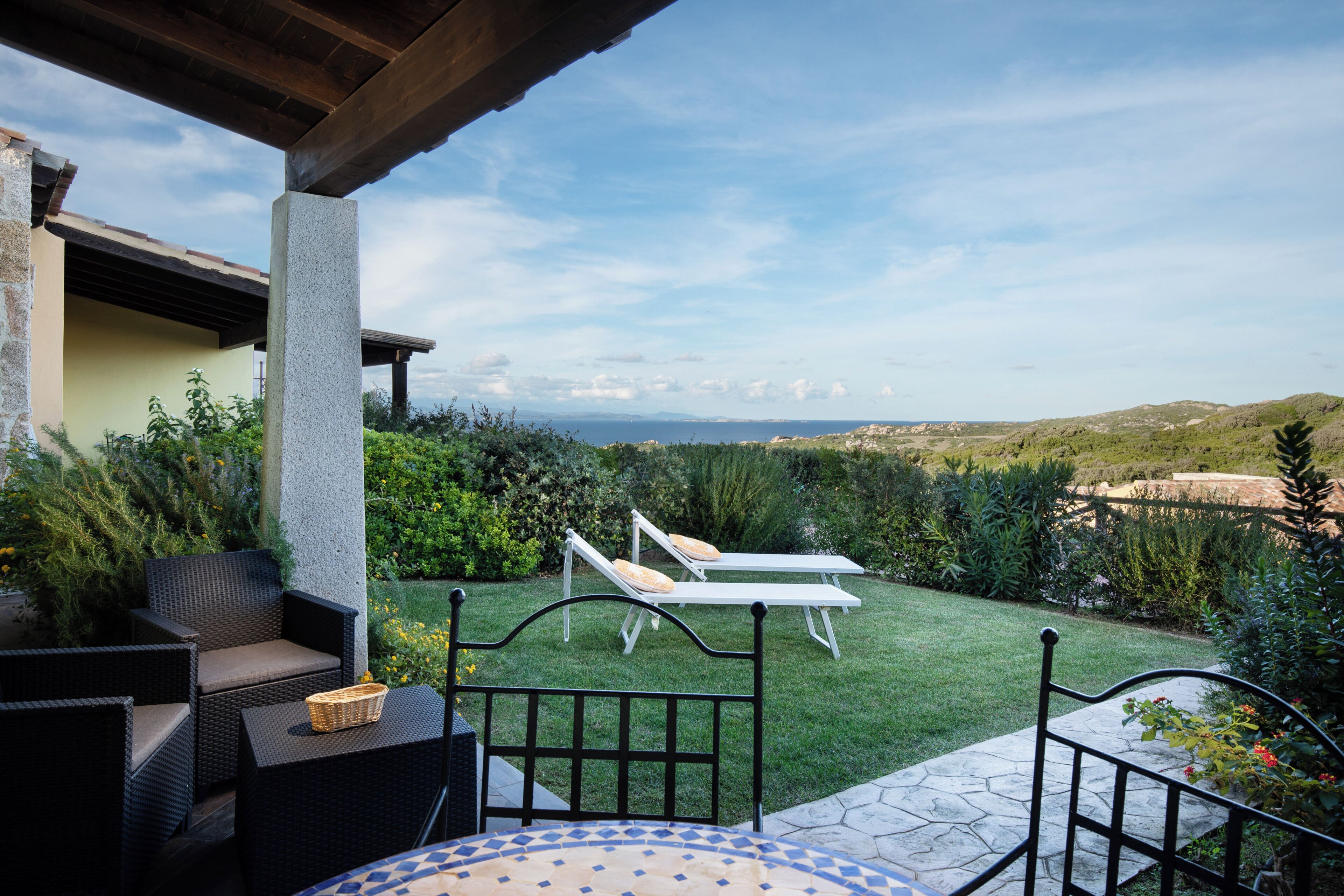 A patio area with outdoor furniture, a view of the landscape, and a stone-tiled table.