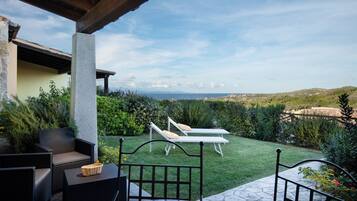 A patio area with outdoor furniture, a view of the landscape, and a stone-tiled table.