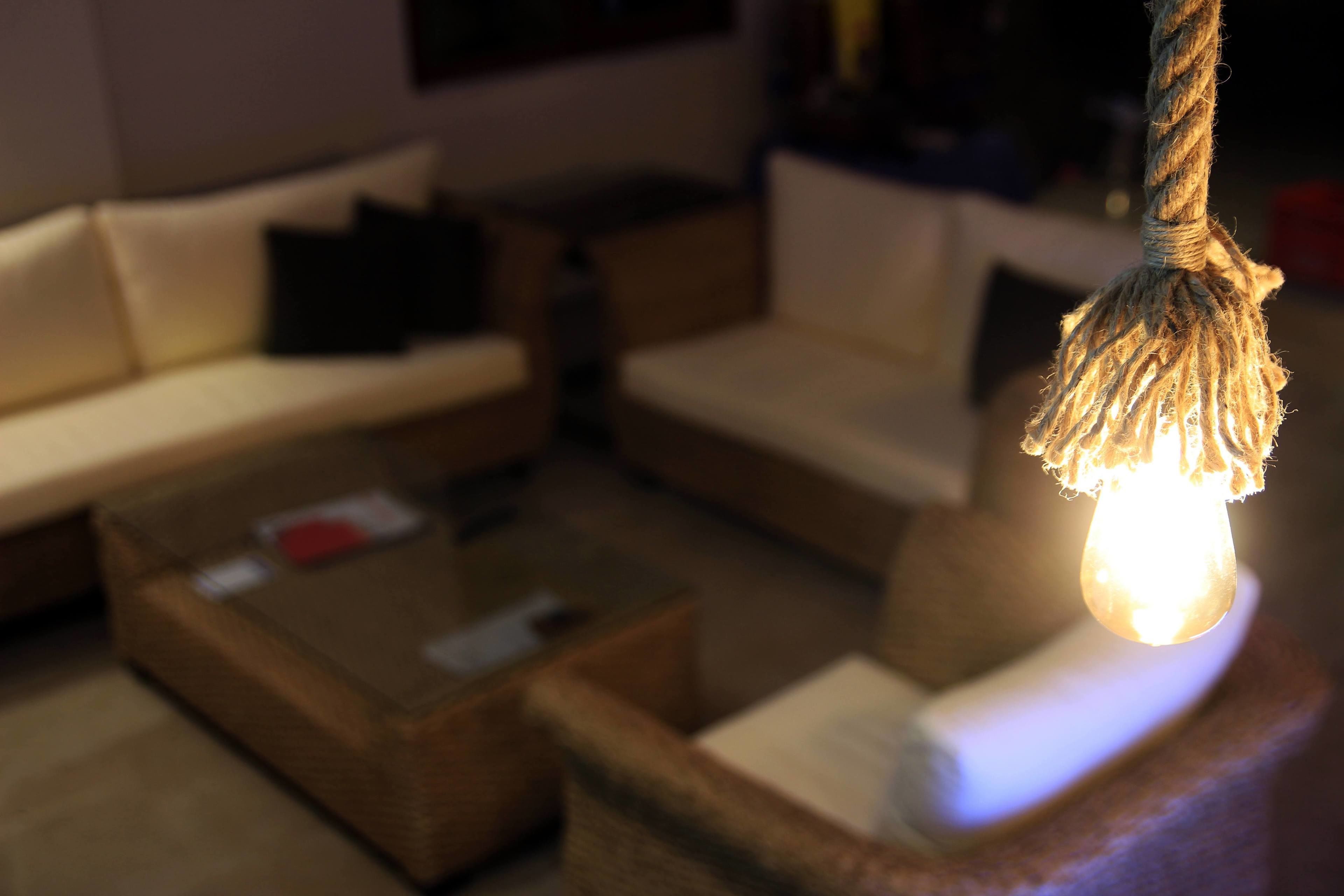 Uma sala de estar com sofá, mesa de centro e luminária pendente.