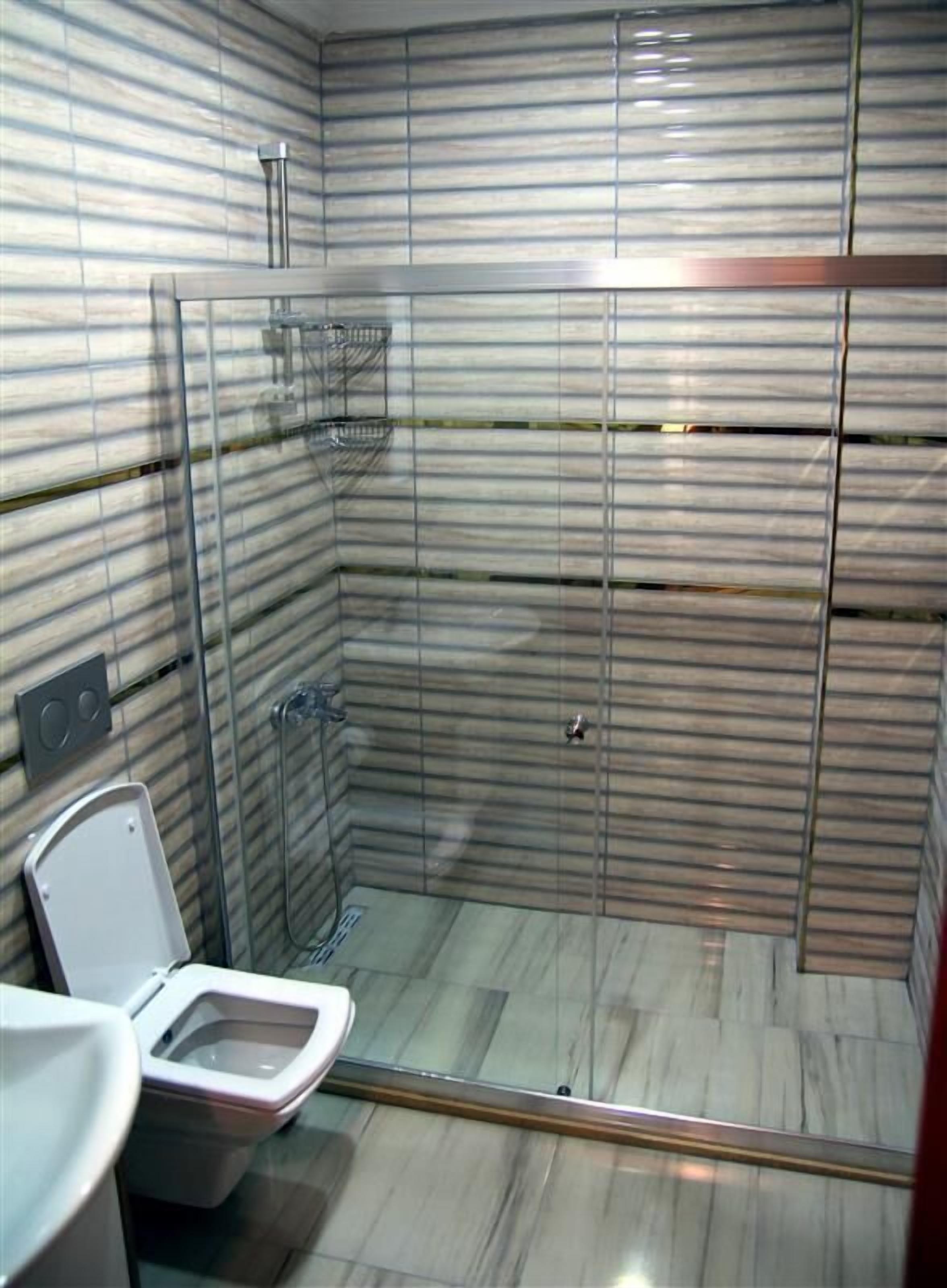 A bathroom with a glass-enclosed shower, a toilet, and a sink.