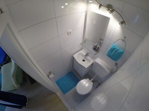 A bathroom with a white sink, toilet, and shower area. - Villa Kale (Split)