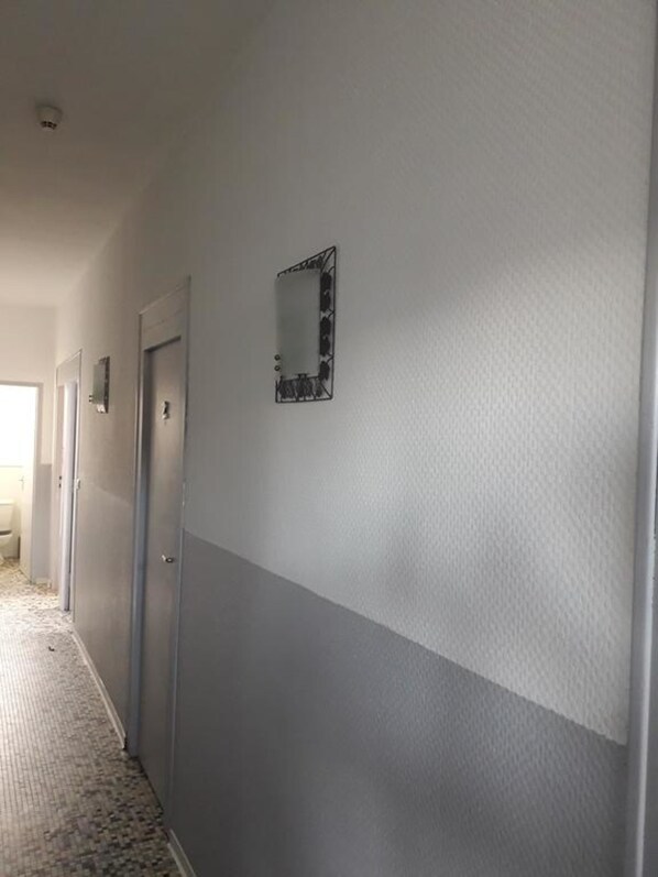 A hallway with a textured wall, a door, and a small mirror. - lO'berge (Mios)