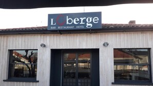 Rakennuksessa on kyltti, jossa lukee: ”LCberge BAR RESTAURANT HOTEL”.