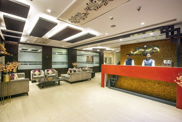 Un lobby moderno con mostrador de recepción, zona de estar y elementos decorativos.