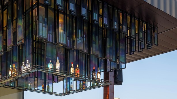 A rooftop bar with a glass railing, bottles, and chairs. -  Vesta Grand Central Udaipur (Udaipur)