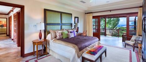 A spacious bedroom with a large bed, a sitting area, and a balcony with a view.