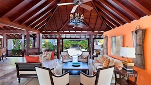 A spacious indoor area with a high ceiling, a central seating arrangement, and a view of the outdoors. - Villa Alila (Holetown)